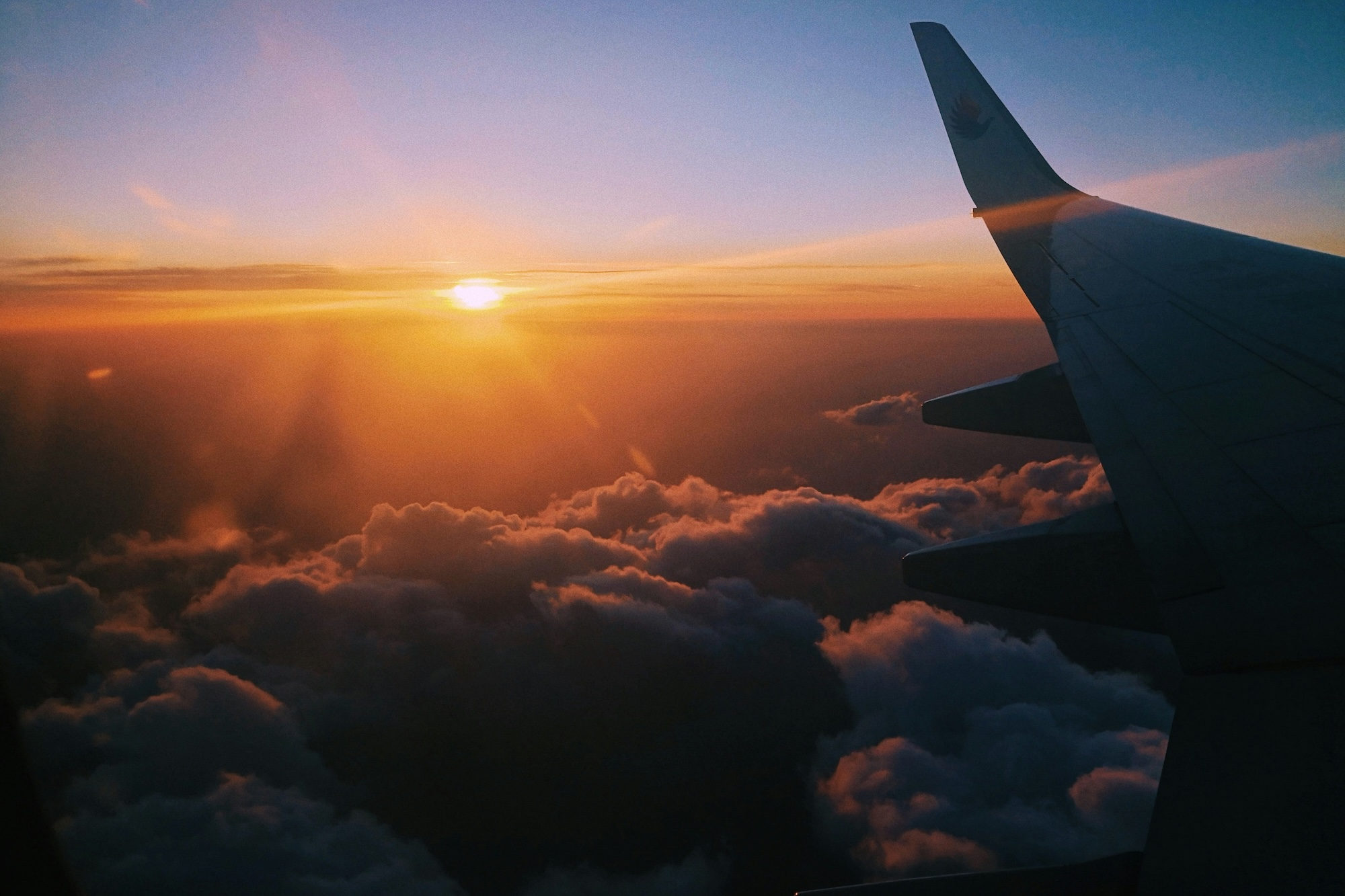 Airplane flying over clouds during golden hour