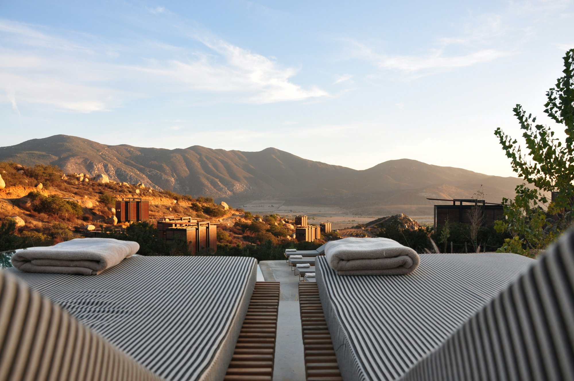Luxury hotel sunloungers overlooking mountain valley at sunset