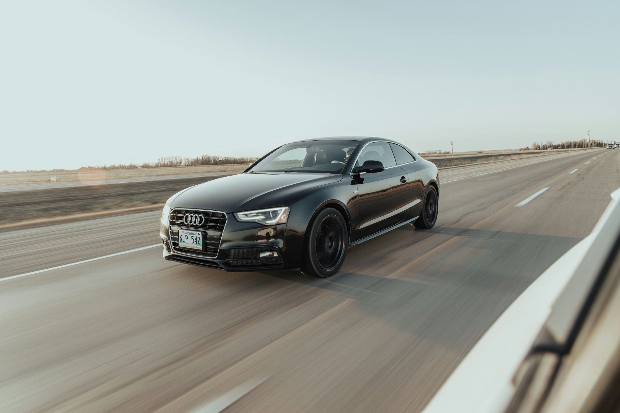 Black Audi coupe driving on a highway at speed
