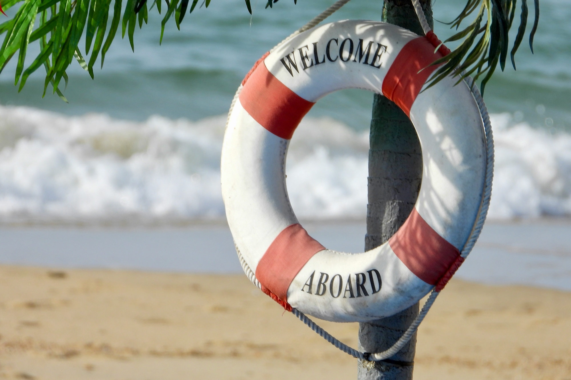 White and orange welcome aboard buoy on a beach