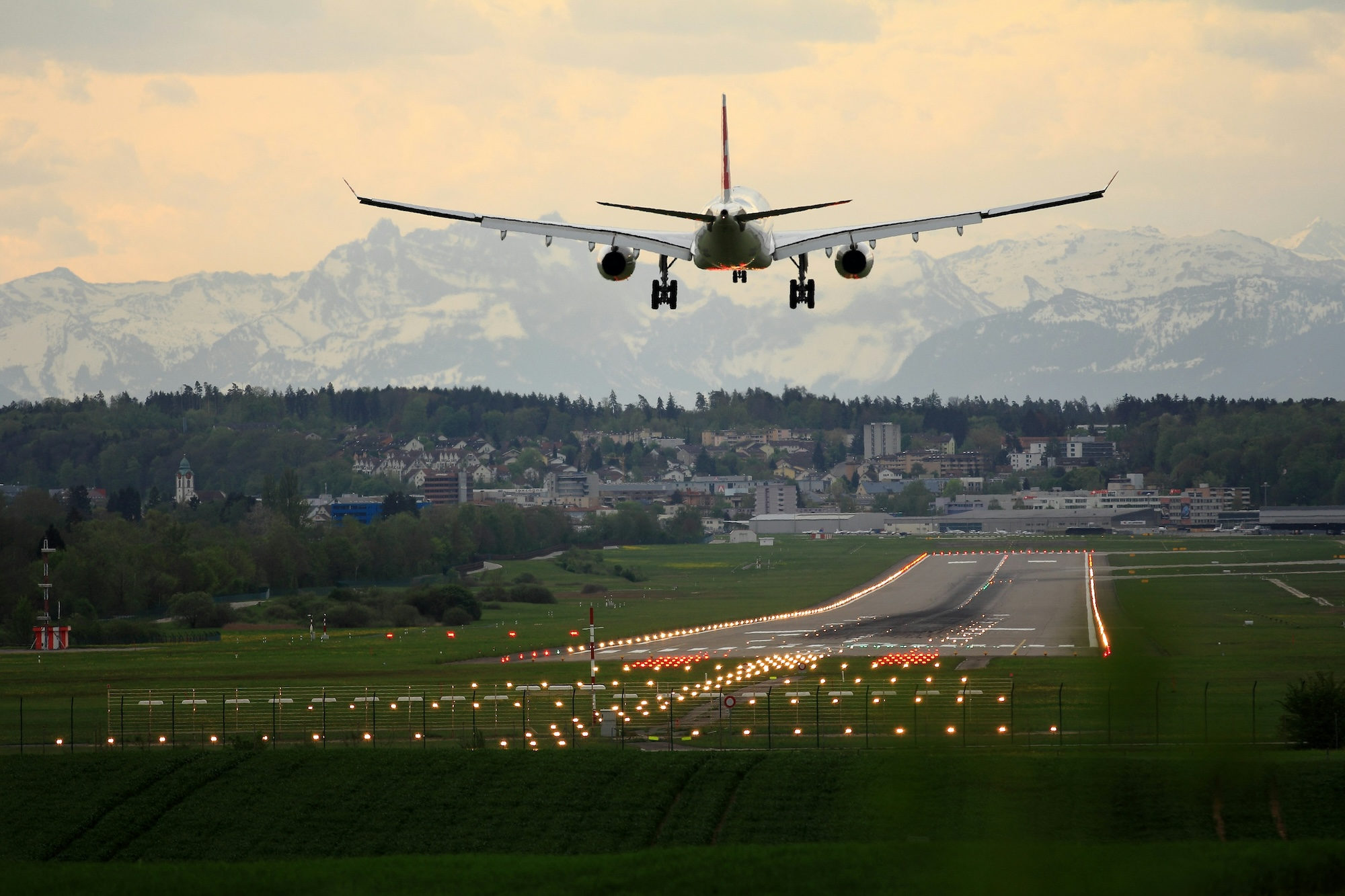 White biplane flying over Swiss mountains