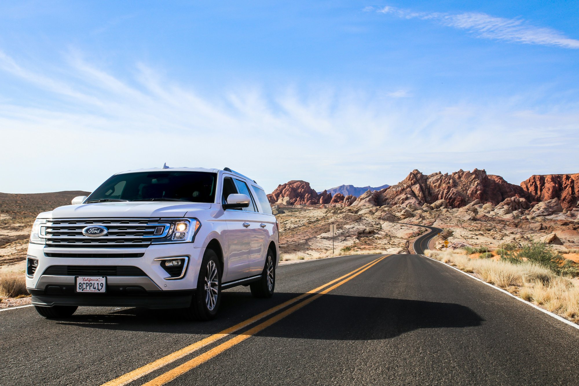White Ford SUV on a desert road with red rock formations in the background